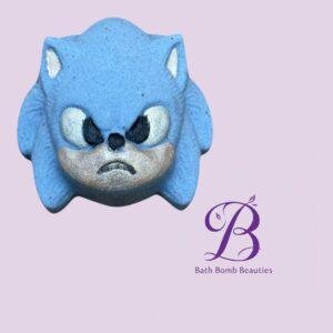 Blue bat-shaped bath bomb with an angry face on a lavender background, featuring the Bath Bomb Beauties logo in purple.