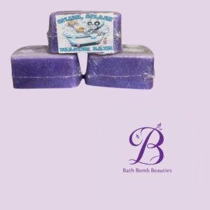 Three purple bath bombs stacked on a pale lavender background, with a Bath Bomb Beauties logo in the lower right.