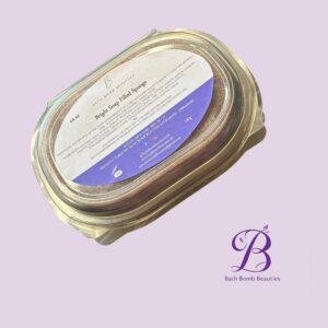 Close-up of a glass jar lid with a white label and Bath Bomb Beauties branding on a light lavender background.