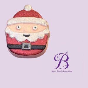 Santa Claus bath bomb with white beard and red suit on a lavender background, positioned in the lower-left with a Bath Bomb Beauties logo in the bottom-right.