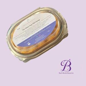 Close-up of a round jar with a white label and purple accent on a pale lilac background, branded Bath Bomb Beauties, suggesting a beauty product