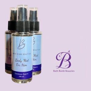 Three bath bomb beauties body mist spray bottles with blue labels arranged on a lavender background brand logo visible in the corner