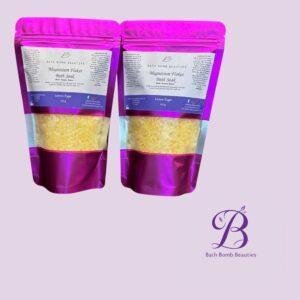 Two pink foil pouches of bath bomb beauties magnesium flakes bath soak in lemon sugar on a lavender background