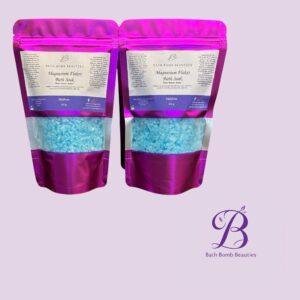 Two pink stand up pouches labeled bath bomb beauties magnesium flakes bath soak with blue bath crystals visible through the lower window