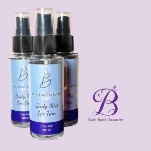 Three Bath Bomb Beauties body mist spray bottles (for him) with blue labels against a lavender background.