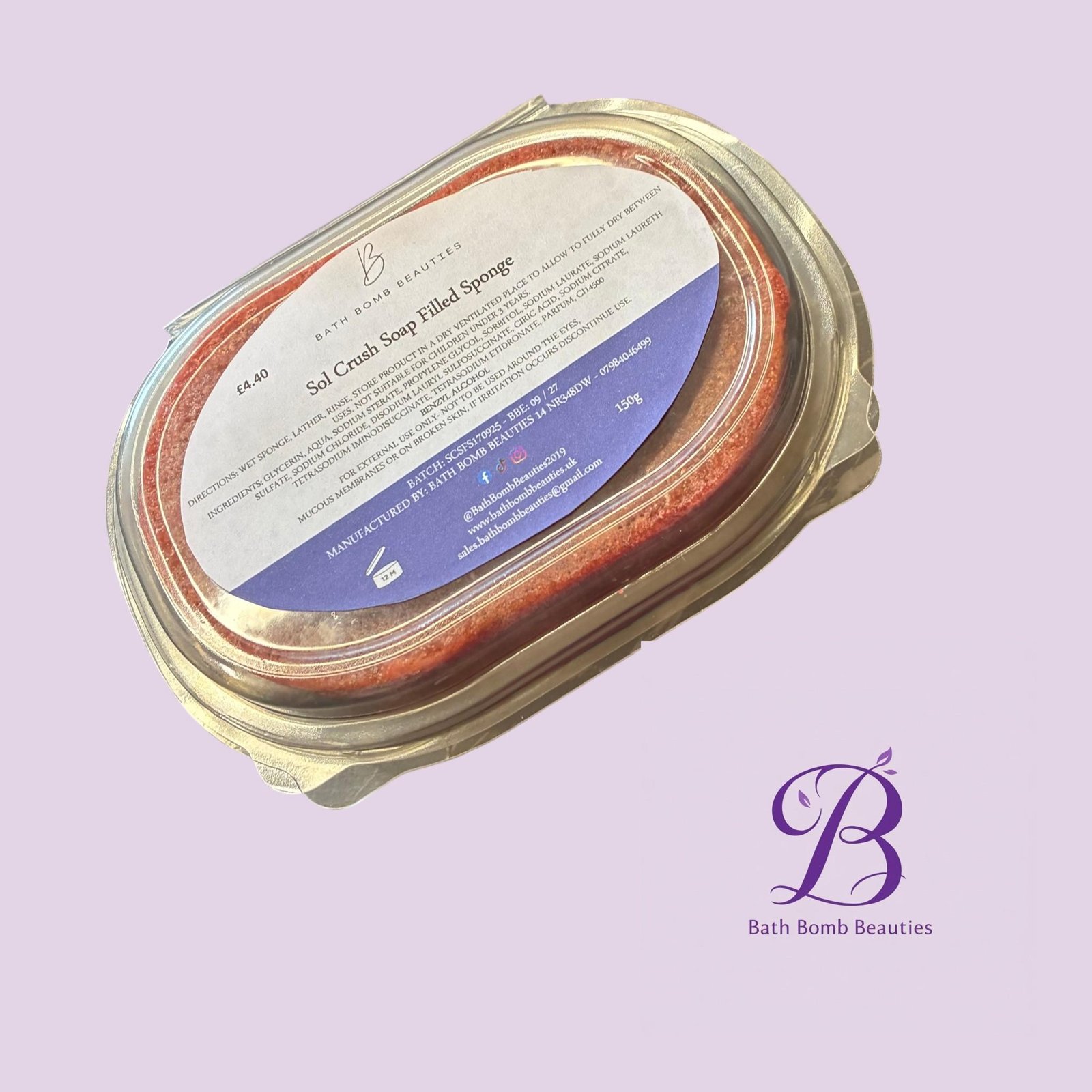 Sol crush norm bath bomb beauties Close up of a glass jar with a metal lid containing a redorange bath bomb set against a light purple background with bath bomb beauties branding visible on the label and backdrop