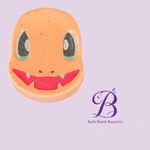 Orange smiley-face bath bomb on a lavender background with the Bath Bomb Beauties logo visible to the right.
