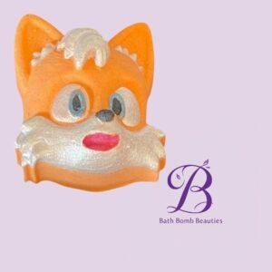 Fox-shaped bath bomb in orange and white on a lilac background, with Bath Bomb Beauties logo nearby.