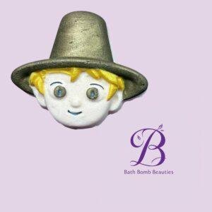 Close up of a cartoon characters head wearing a gold hat on a pastel purple background with the bath bomb beauties logo nearby