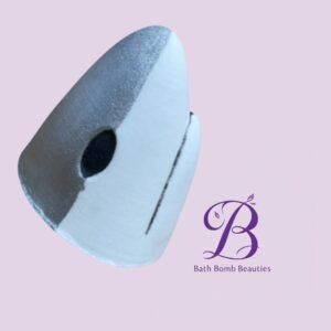 Close-up of a two-tone, spherical bath bomb slice in white and gray on a light pink background, with a purple Bath Bomb Beauties logo in the corner.