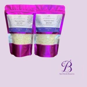 Two magenta resealable pouches labeled bath bomb beauties magnesium flakes bath soak set against a pink lavender background with logo