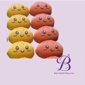 Kawaii yellow and pink bath bombs with smiling faces on a lavender backdrop, featuring Bath Bomb Beauties branding.