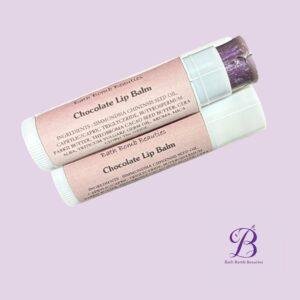 Chocolate lip balm bath bomb beauties Two pink chocolate lip balm tubes overlapping on a lavender background with bath bomb beauties logo in the corner product image