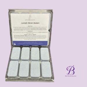 Lavender shower steamers bath bomb beauties Box of lavender shower steamers by bath bomb beauties in a metal tin with lavender scented tablets lavender background and logo in corner