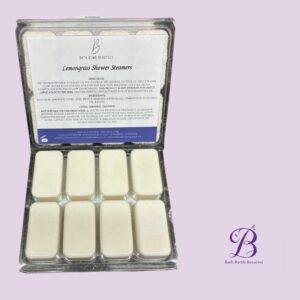 Lemongrass shower steamers bath bomb beauties Lemongrass shower steamers in a clear plastic tray on a lavender background bath bomb beauties branding visible on the label and corner of the image