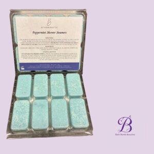 Peppermint shower steamers bath bomb beauties Open tin of peppermint shower steamers turquoise rectangular tablets sit in a metal tin on a purple background with bath bomb beauties logo