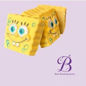 Two yellow sponge shaped bath bombs with faces and blue circles on a lavender background bath bomb beauties logo visible