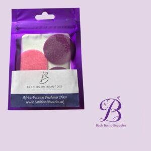 Purple resealable pouch containing pink and purple Bath Bomb Beauties Africa Vacuum Freshener Discs, with the Bath Bomb Beauties logo visible.",
