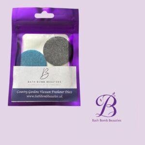 Purple resealable pouch containing blue and gray vacuum freshener discs with a Bath Bomb Beauties label on the front, set against a lavender background.