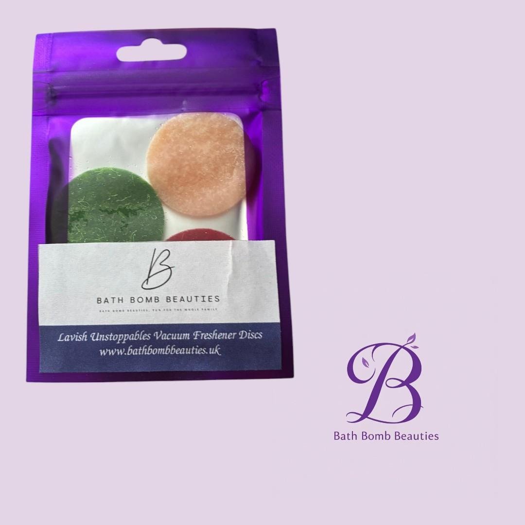 Lavish unstoppables bath bomb beauties Purple resealable pouch with a clear window showing three bath bomb discs green peach red and a bath bomb beauties label lavender background
