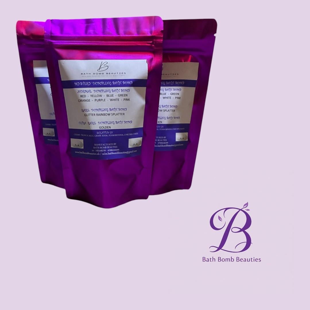 Mystery squishy dumplings bath bomb beauties Three purple stand up pouches of bath bomb beauties on a lavender background with a blue and white product label and a decorative b logo in the corner