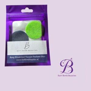 Rosey wonderland bath bomb beauties Purple resealable bag containing two bath bomb discs green and dark gray with bath bomb beauties branding visible against a lavender background