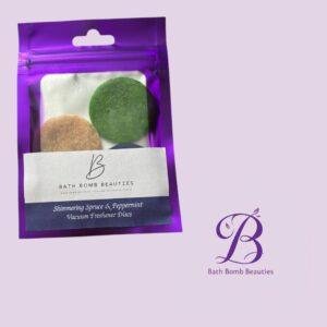 Shimmering spruce peppermint bath bomb beauties Purple resealable pouch containing bath bomb beauties vacuum freshener discs label reads shimmering spruce peppermint vacuum freshener discs signature b logo in corner