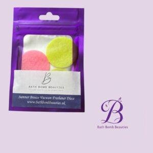 Purple resealable pouch containing pink and yellow bath bomb beauties discs set against a lavender background with the logo visible