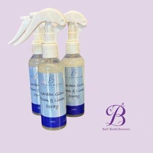 Three white spray bottles with blue labels reading lawn glow room  linen spray by bath bomb beauties against a lavender backdrop arranged in a row with the logo visible