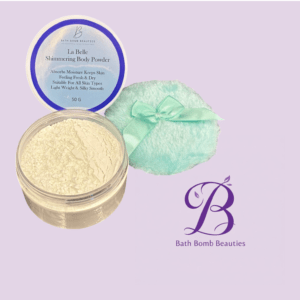 Open jar of pale shimmering body powder labeled la belle with a mint towel tied with a ribbon and bath bomb beauties logo on a lavender background