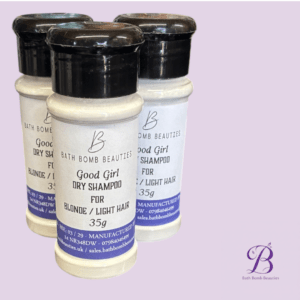 Three bottles of bath bomb beauties good girl dry shampoo for blondelight hair arranged against a lavender background with the brand logo in the corner